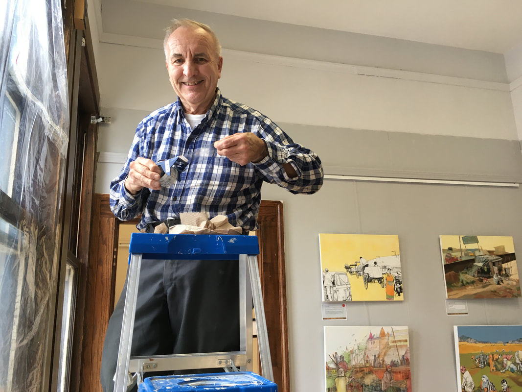 Don Bailey on ladder fixing windows in gallery